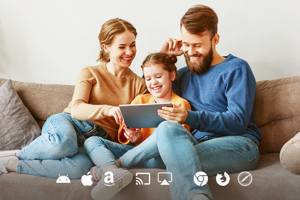 Familie sitzt auf dem Sofa und schaut auf ein Tablet