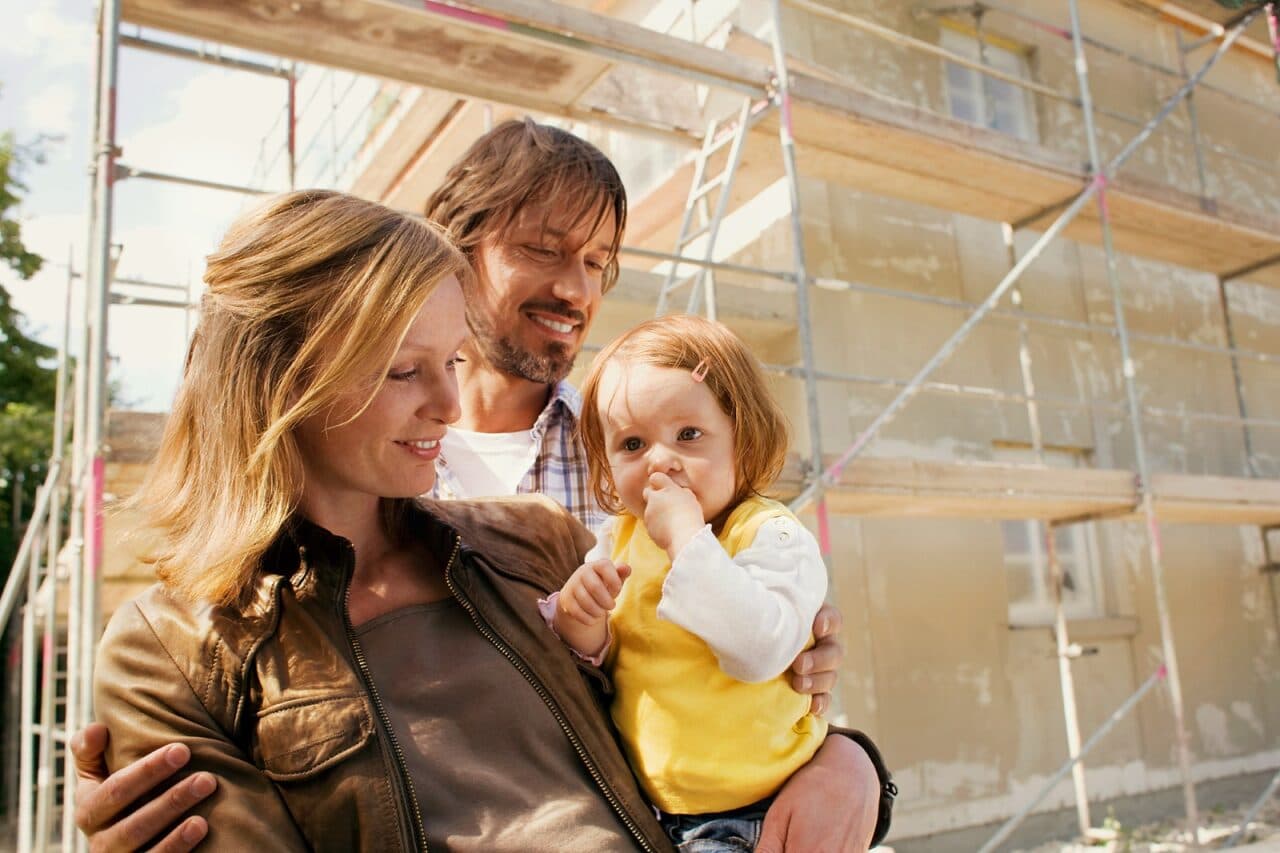 Familie mit Kleinkind steht vor einem Baugerüst