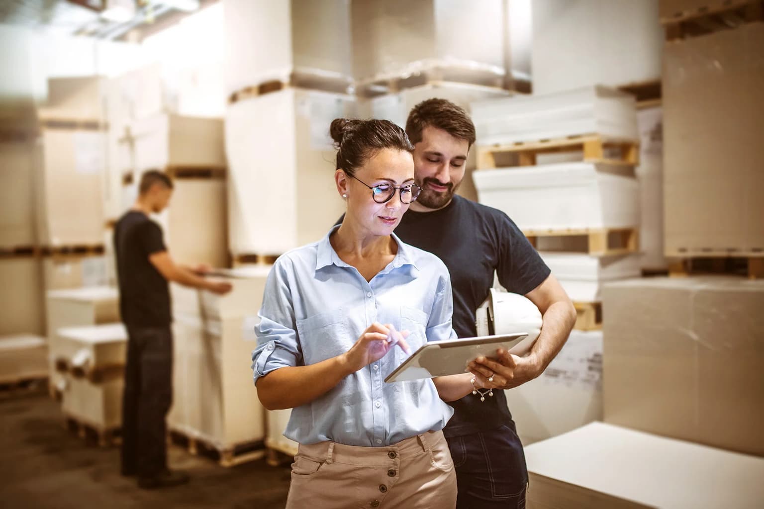 Zwei Personen checken den Status auf dem Laptop in der Lagerhalle für Kartons