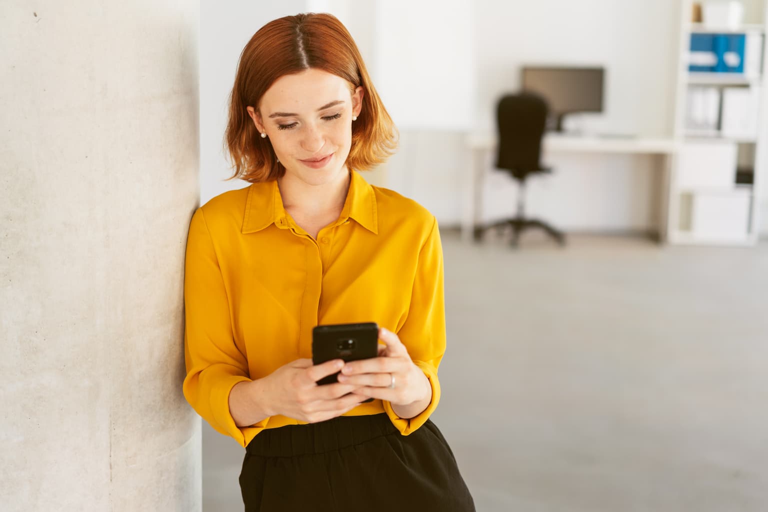 Digitale Transformation - Frau in gelber Bluse lehnt an der Wan