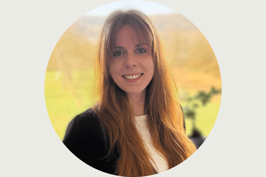 Das Bild ist das Porträt einer Mitarbeiterin. Es sind Gesicht und Schultern zu sehen. Der Hintergrund ist verschwommen.