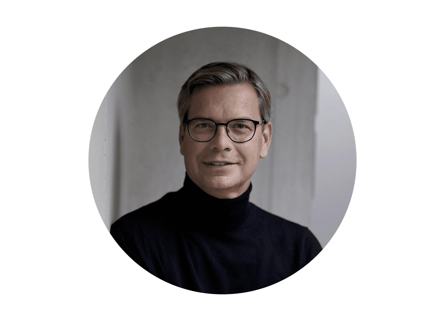Porträtfoto einer Person mit Brille in schwarzem Rollkragenpullover vor hellem Hintergrund in kreisrundem Format.