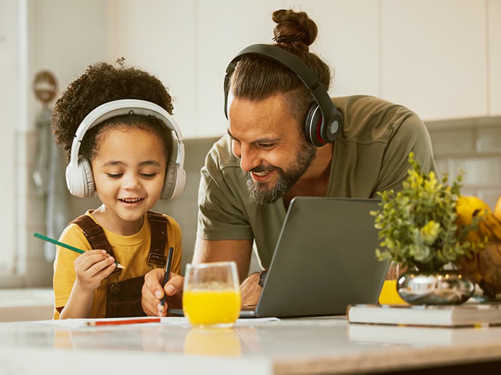 Vater und junge Tochter malen zusammen in der Küche und hören Musik