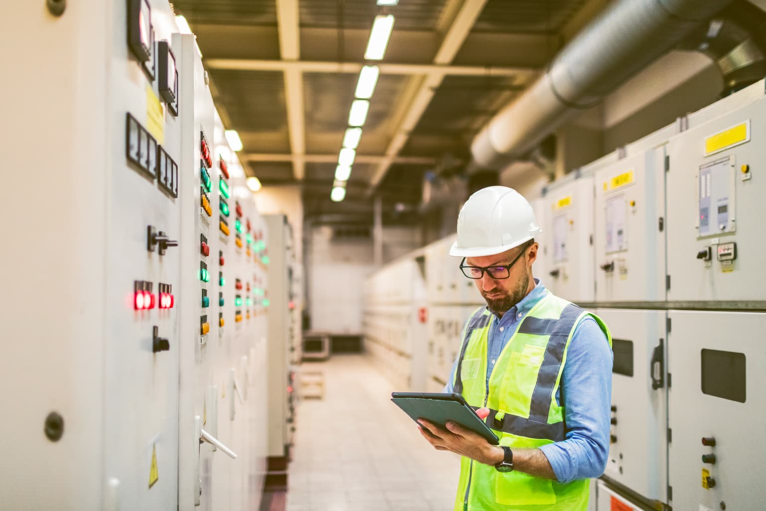 B2B Standortvernetzung MPLS & VPN, Bauarbeiter in einer Fabrikhalle kontroliert die Maschinen