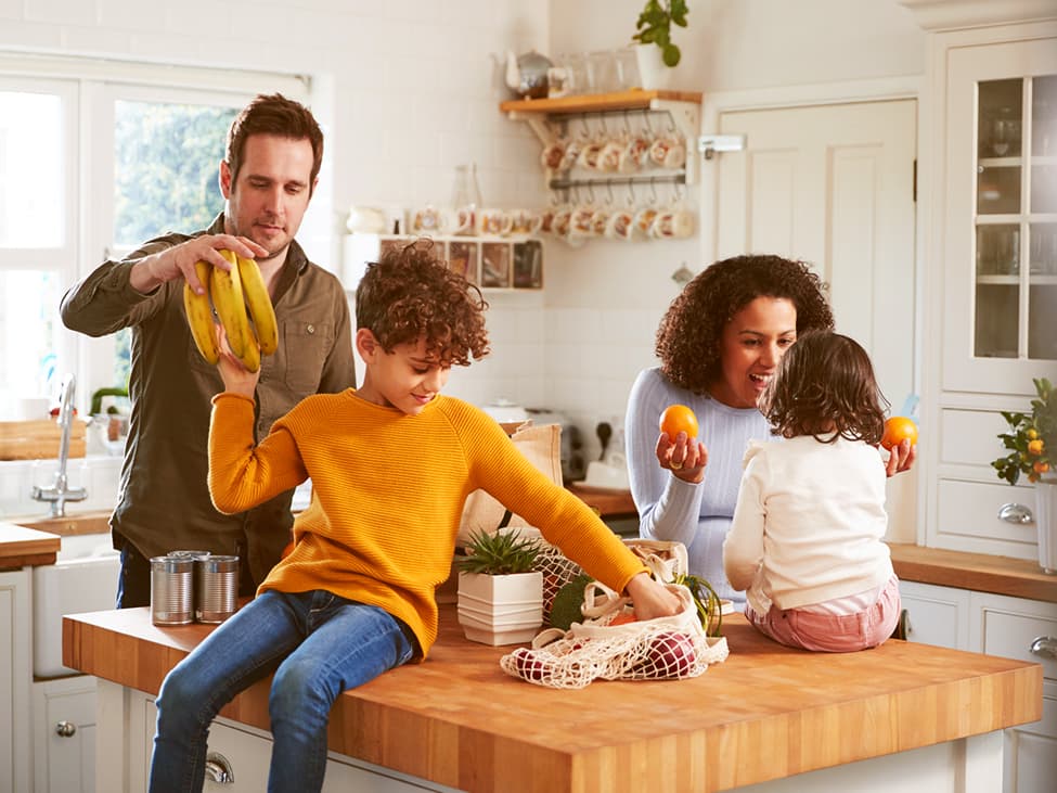 Vier-köpfige Familie ist in der Küche und packt die Einkäufe aus