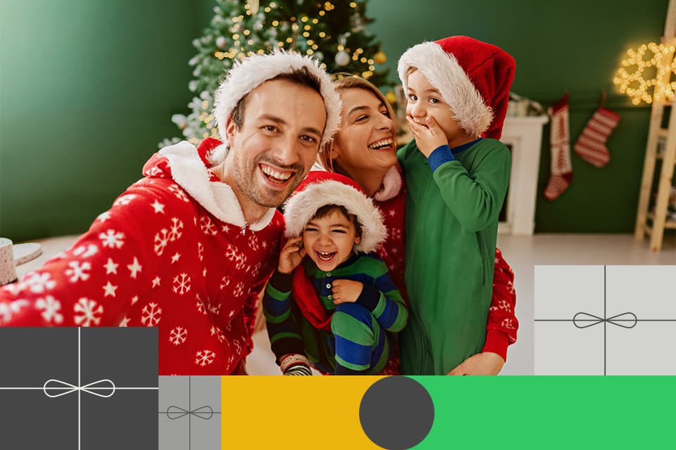 Familie in Weihnachtskleidung lächelt vor geschmücktem Tannenbaum, alle tragen Weihnachtsmützen in festlicher Atmosphäre.