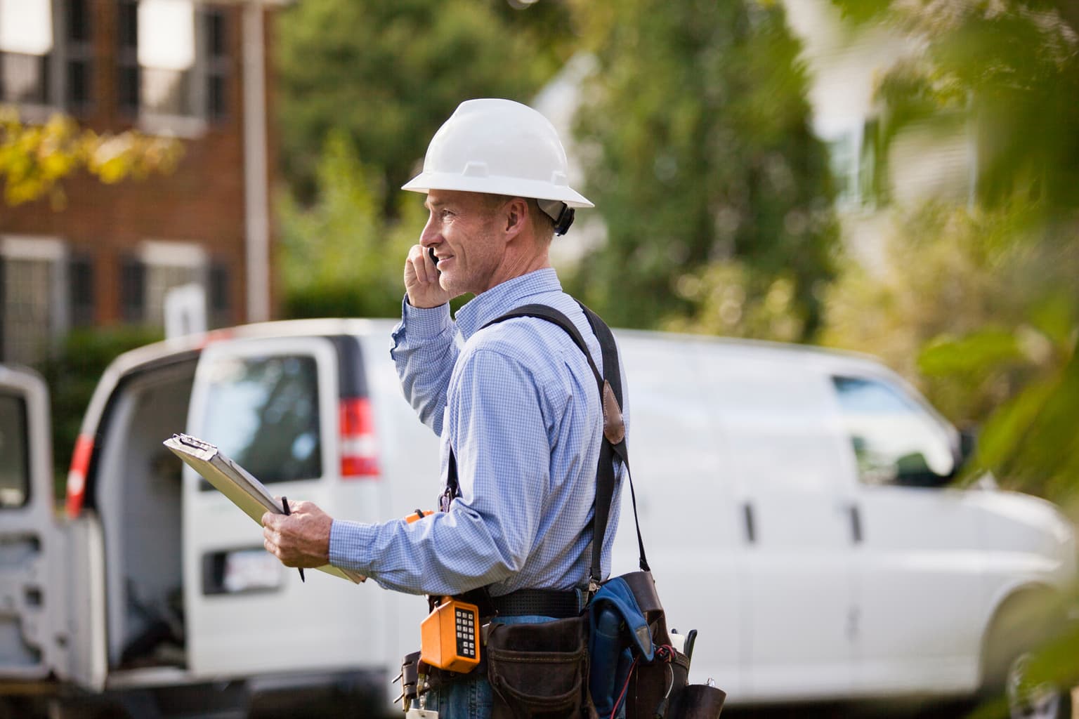 Bauarbeiter telefoniert und hält seine Notizen hoch