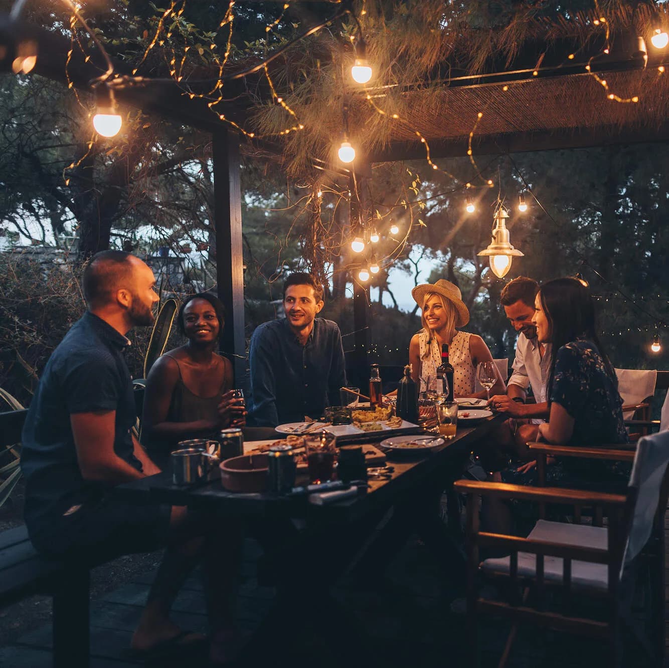 Freunde sitzen auf der Terrasse am Abend bei Licht und reden