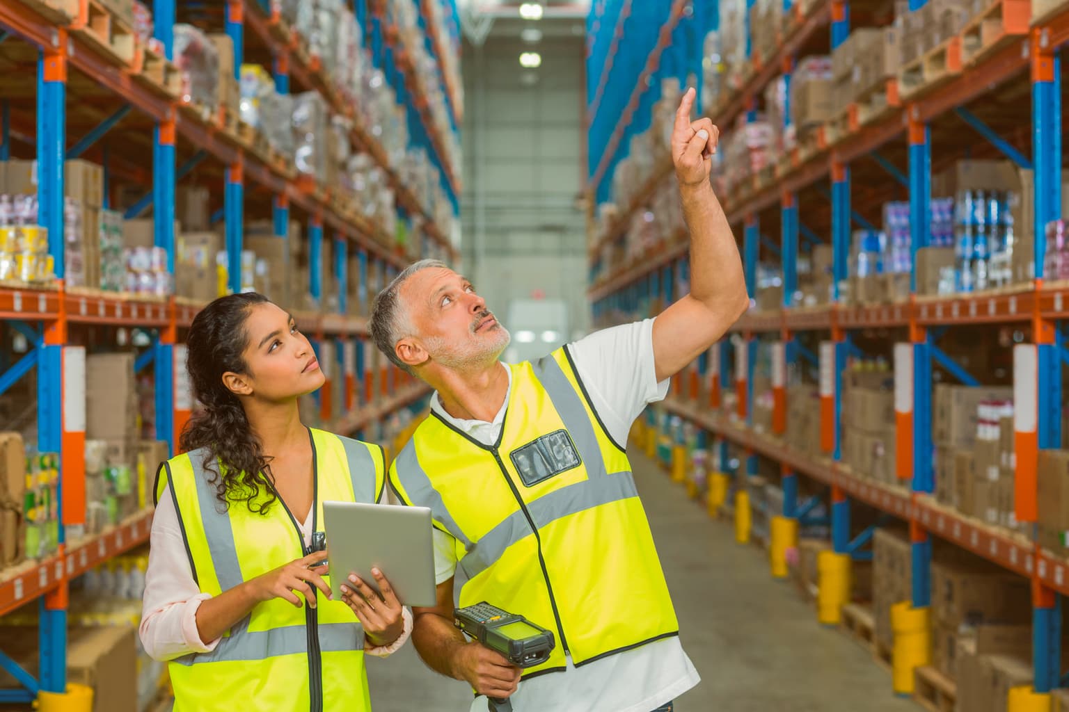 Wettbewerbsvorteile für große Unternehmen 2 Arbeiter tragen Warnwesten und gehen durch eine Lagerhalle
