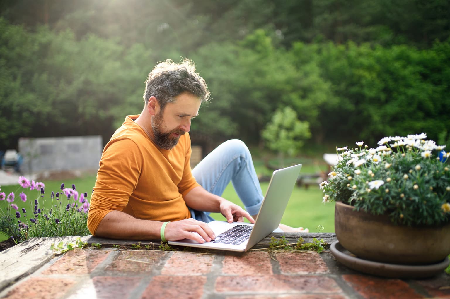 Mann sitzt am Laptop im Garten