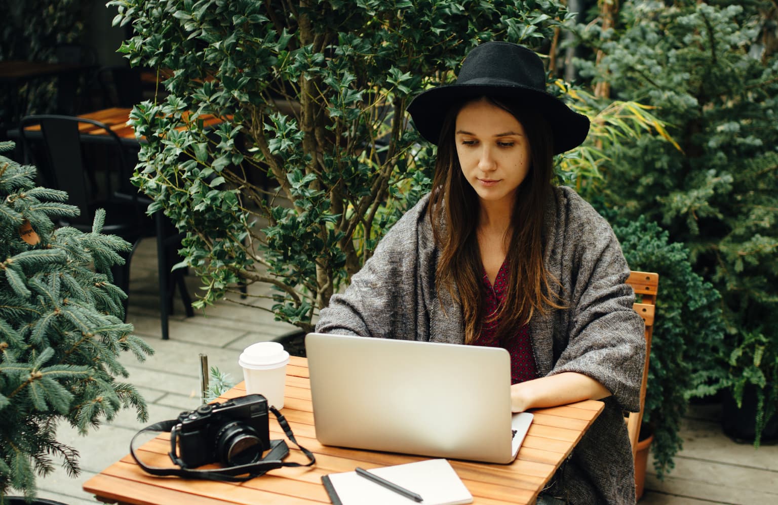 Frau mit Hut sitzt am Laptop und informiert sich über Ihre Rechnungen