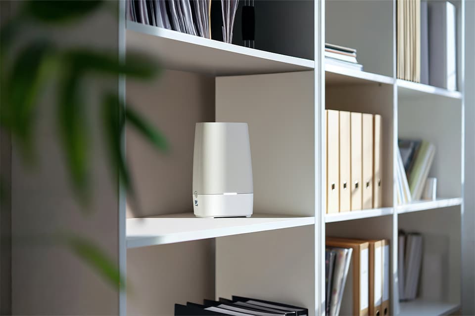 Weißer Router auf einem minimalistischen Bücherregal mit Ordnern und Dokumenten in einem modernen Büro.