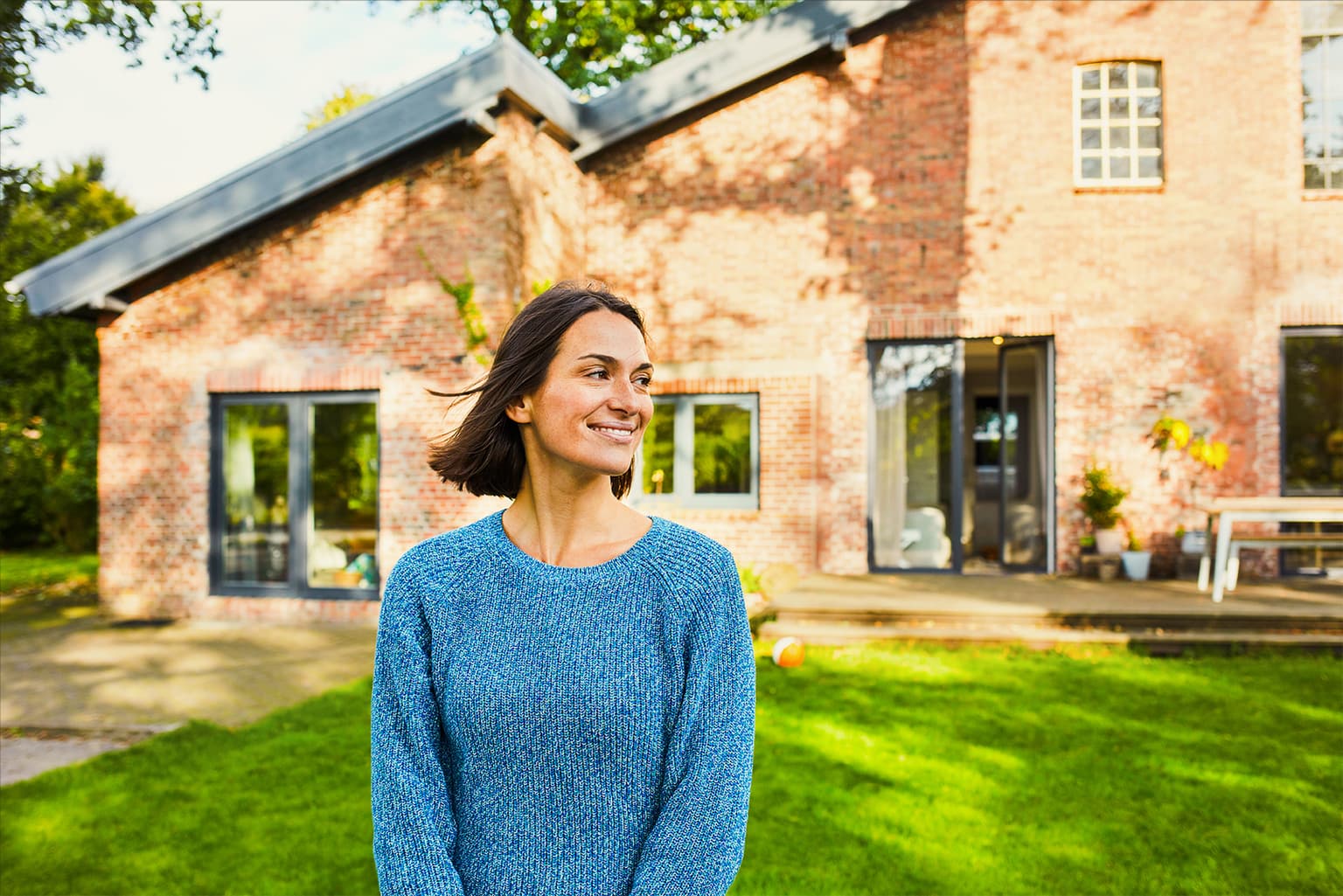 Frau steht lachend vor ihrem Haus 2