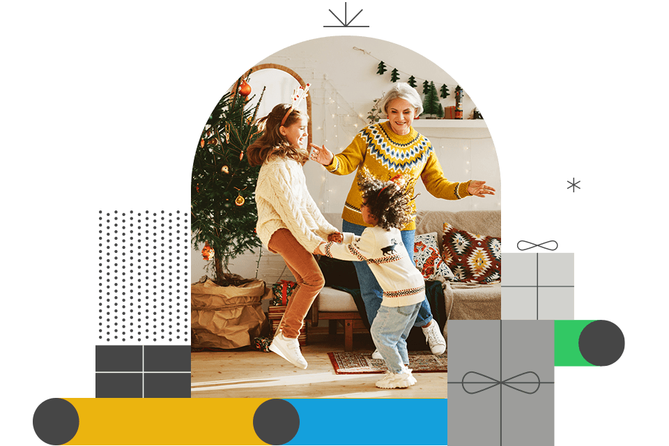 Familie tanzt fröhlich im weihnachtlich dekorierten Wohnzimmer mit geschmücktem Tannenbaum und festlichen Pullovern.