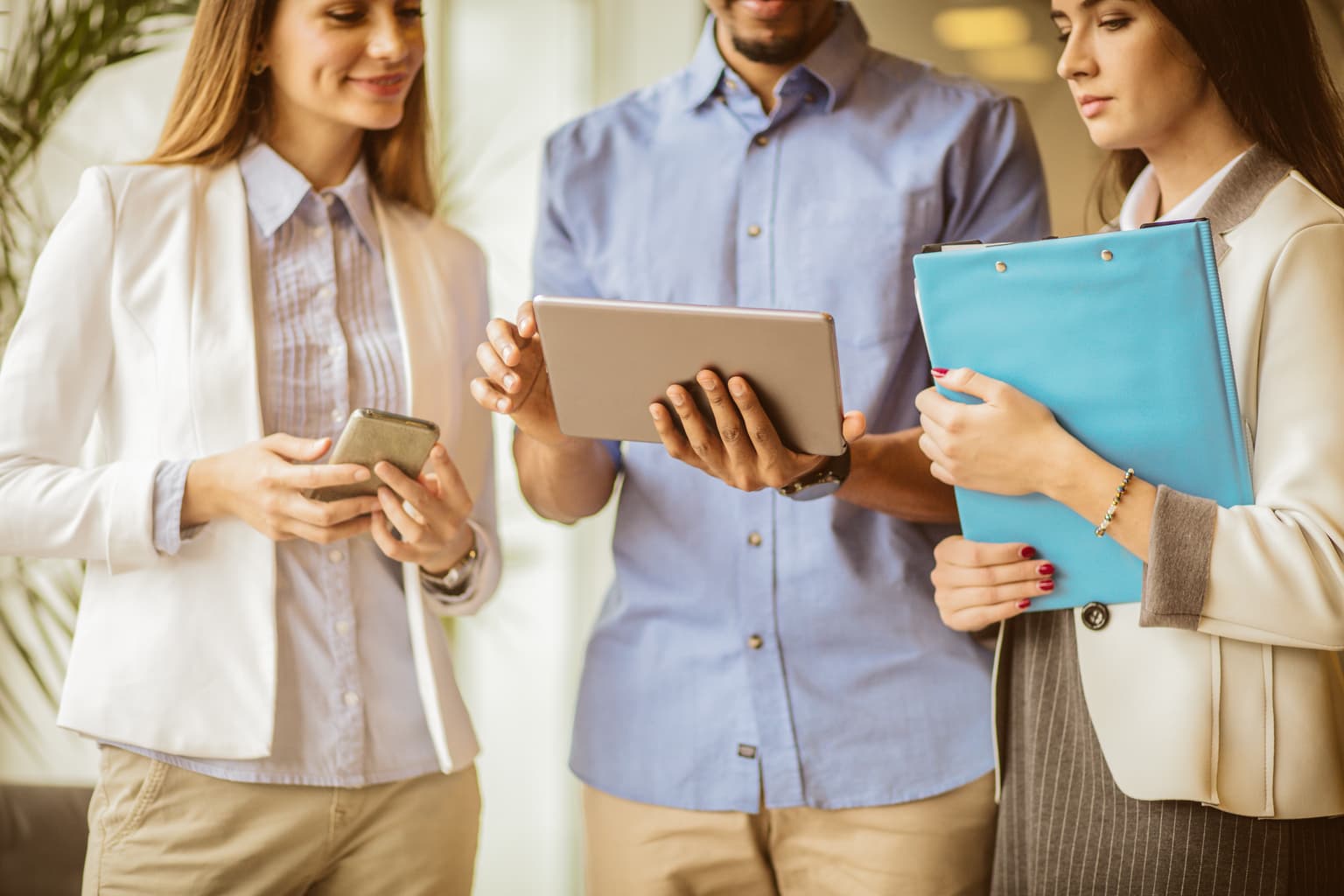 Arbeitskollegen schauen zusammen auf ein tablet im Bürogang