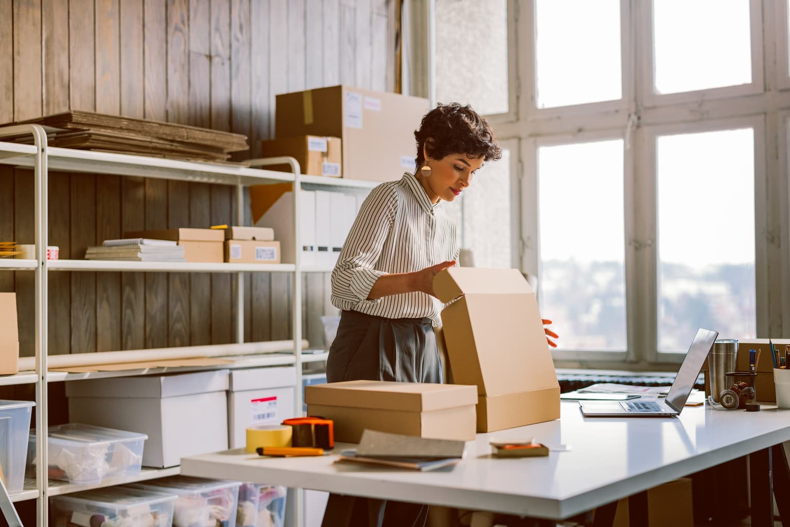 Frau packt Kartons ein in einer Lagerhalle