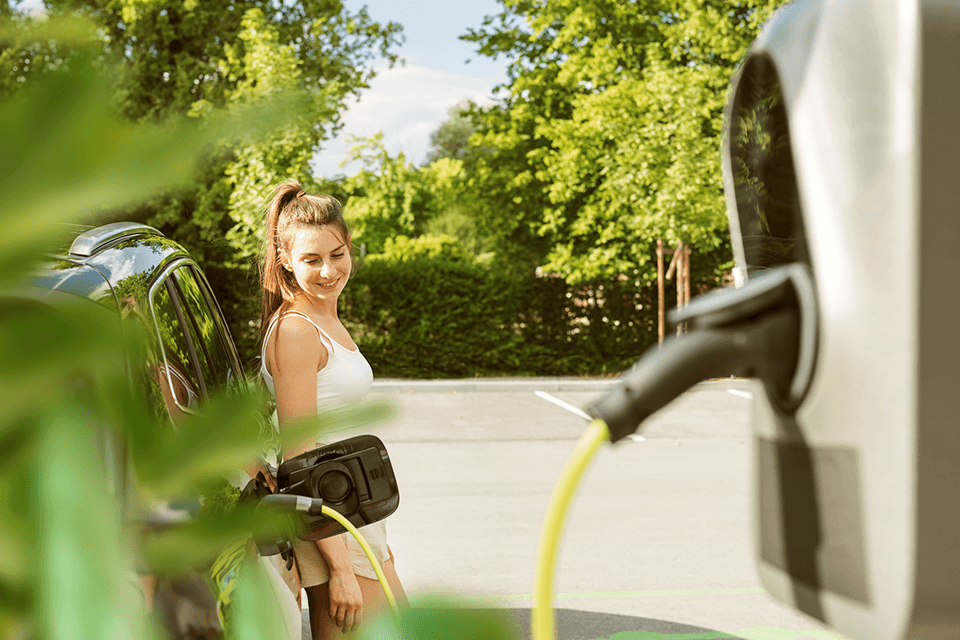 Frau lädt ihr Elektro-Auto an der Zapfsäule