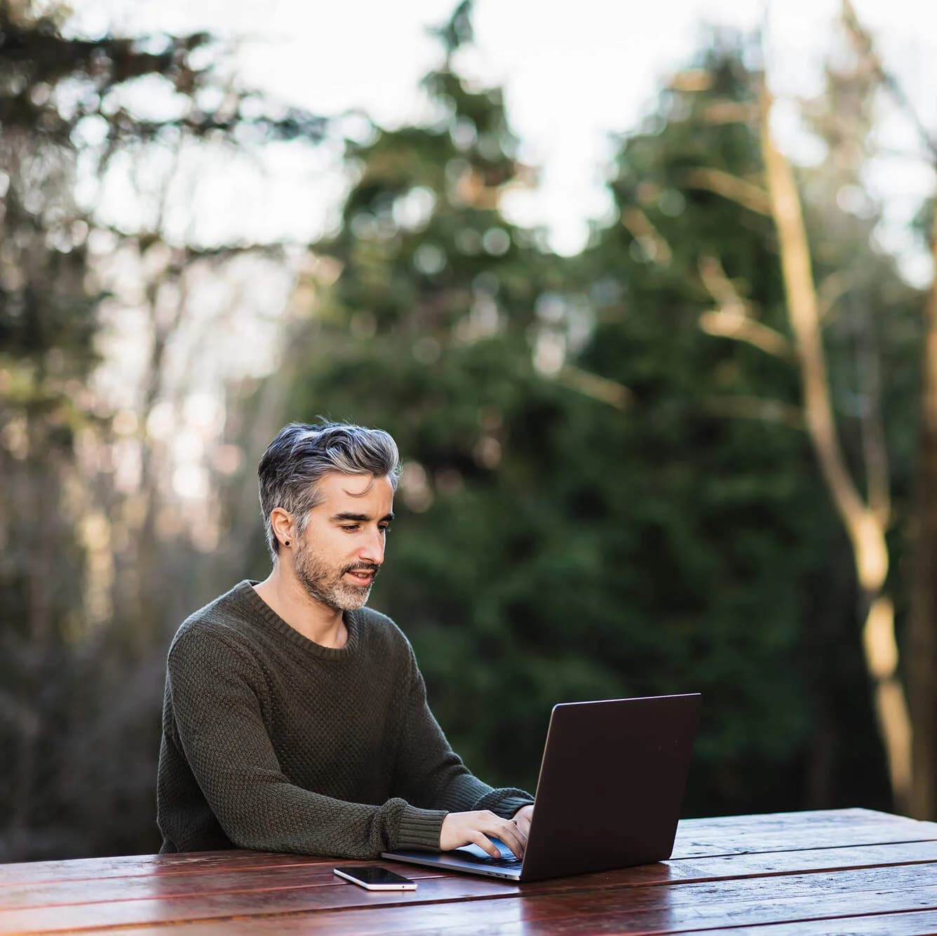 Man sitzt an einem Tisch in der Natur und arbeitet am