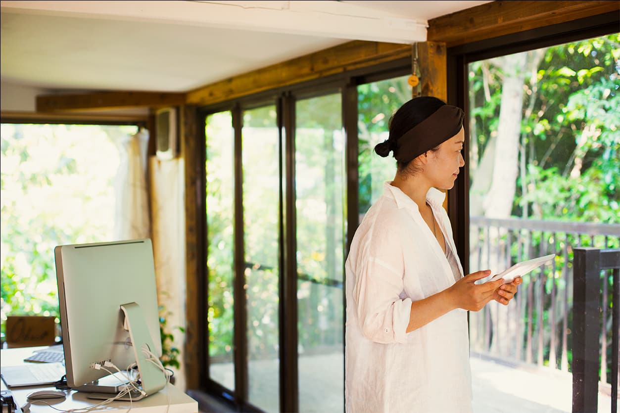 Frau schaut aus ihrem Fenster im Homeoffice Büro