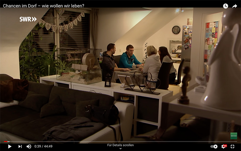 Szene aus dem Film: Eine vierköpfige Familie sitzt am Tisch unter einer Dachschräge