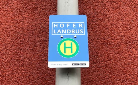 Haltestellenschild mit der Aufschrift „Hofer Landbus“ und „Jetzt die App laden“