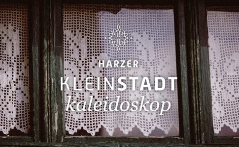 Holzfenster mit Häkelgardine und Aufschrift „Harzer Kleinstadtkaleidoskop“