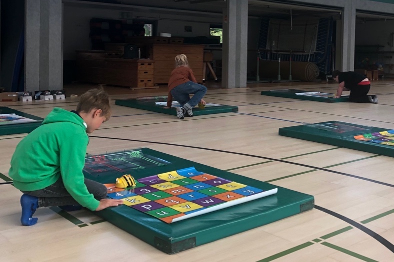 Kinder mit Lernmaterialien in einer Turnhalle
