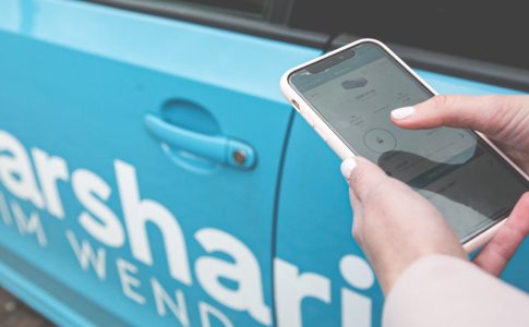 Eine Person öffnet mit Hilfe des Smartphones ein Carsharing-Fahrzeug