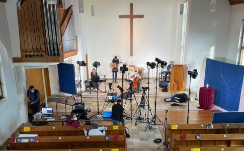Eine Band bereitet sich in einer Kirche auf einen Auftritt vor, Beleuchtung und Tontechnik werden eingerichtet.
