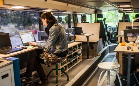 Blick in den Doppeldeckerbus Fabmobil. Eine Frau am Laptop und technisches Gerät ist zu sehen.)