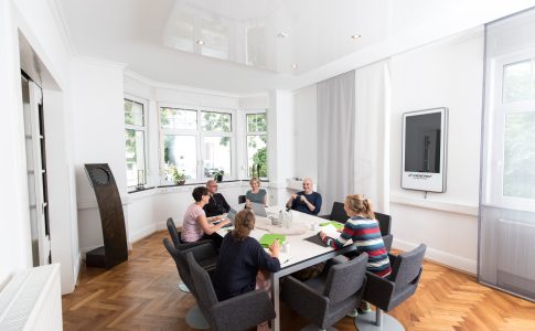 Männer und Frauen sitzen in einem Konferenzraum um einen Tisch zusammen.