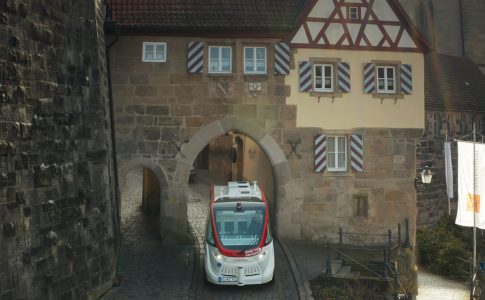 Ein modernes, selbstfahrendes Shuttle fährt durch ein historisches Altstadtgebiet