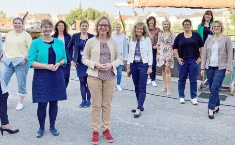 Eine Gruppe Bürgermeisterinnen steht auf einer Hafenpromenade.