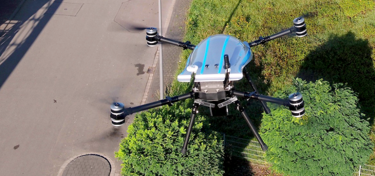 Eine Drohne mit Kamera fliegt über Bäumen.