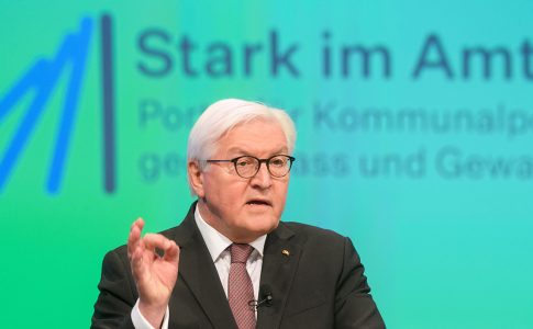 Vor einer Wandprojektion steht Bundespräsident Frank-Walter Steinmeier mit einem Tablet in der Hand.