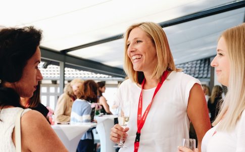 Drei Frauen stehen auf einer Terrasse und unterhalten sich.