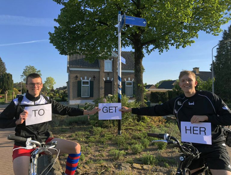 Alt: Zwei junge Fahrradfahrer treffen sich an einem Wegweiser und halten Zettel mit der Aufschrift „together“ in die Höhe