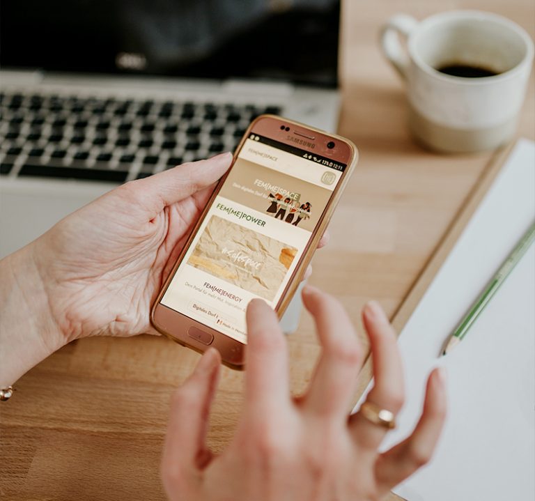 Eine Hand hält ein Smartphone, auf dem der Femmespace-Onlineauftritt mit einer Kartenansicht zu sehen ist.