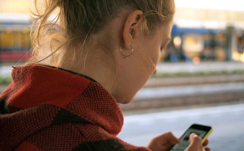 Eine Frau schaut auf das Smartphone in ihren Händen.