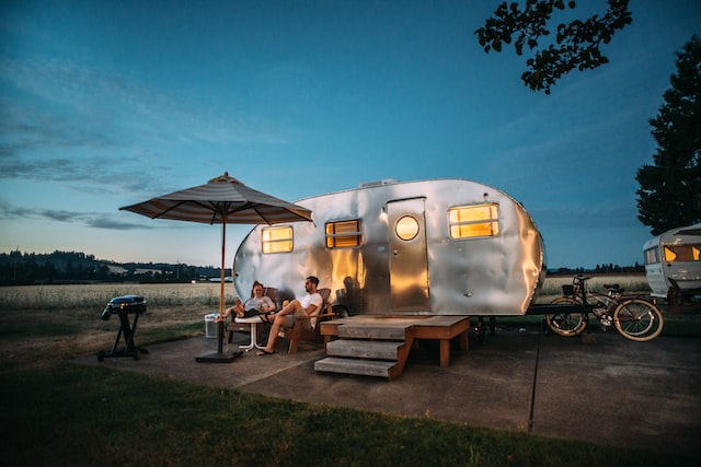 Foto von Frau und Mann vor ihrem Camper in der Abenddämmerung