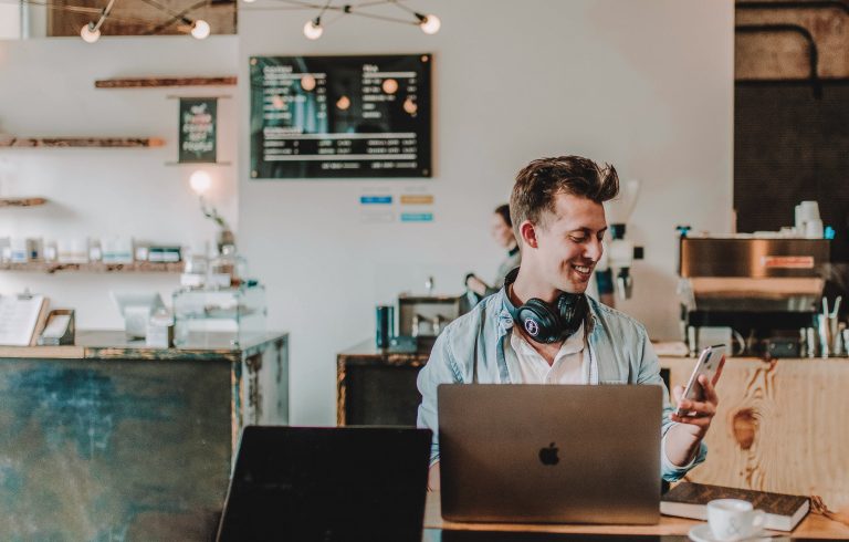 Mann an Tisch mit Laptop in Café