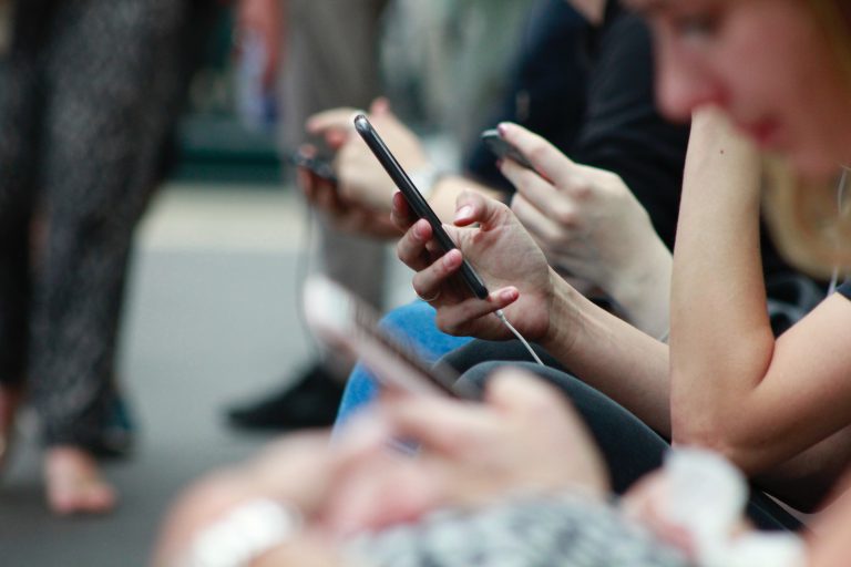 Mehrere junge Menschen halten Smartphones in den Händen.