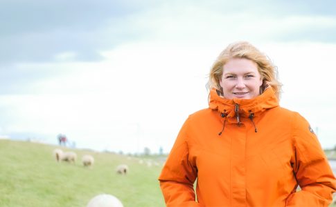 Frau in orangener Jacke lächelt