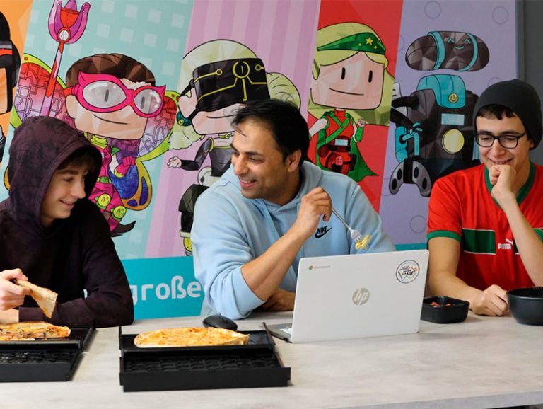 Rinku Sharma und zwei Jugendliche schauen in einen Laptop.