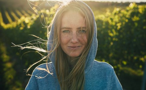 Portrait Juliane Eller vor einem Weinberg in der Abendsonne.