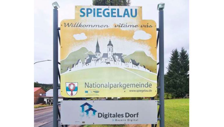 Ortseingangsschild Spiegelau, darunter Schild mit Logo und Schriftzug der Initiative „Digitales Dorf“