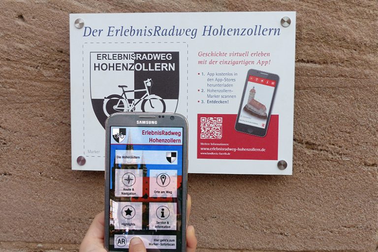 Smartphone vor Schild mit dem Marker der Hohenzollern-Radweg-App
