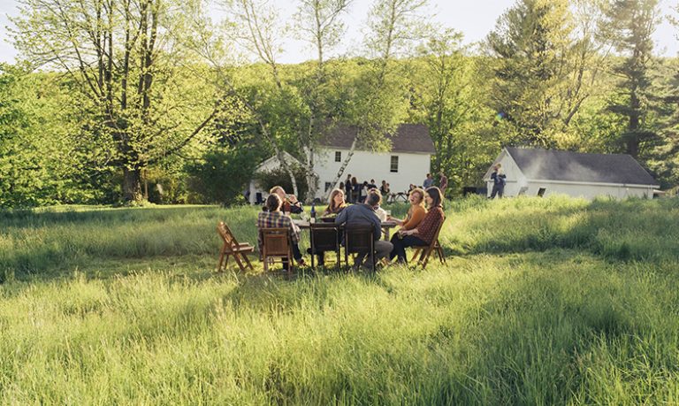 Gruppe von Menschen an einem Tisch auf großer Wiese