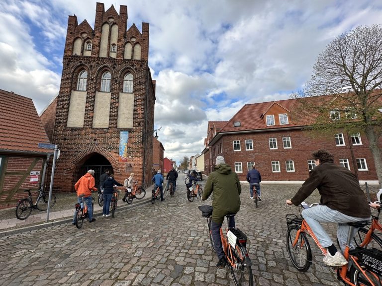 Menschen fahren mit einem Fahrrad durch eine Altstadt.