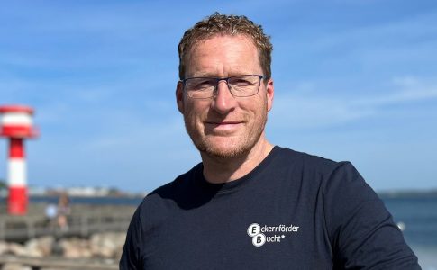 Mann am Meer, im Hintergrund Strand der Eckernförder Bucht